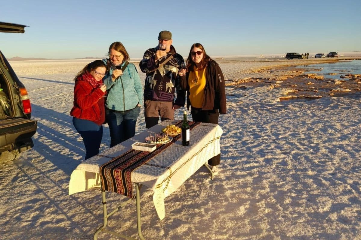 Brindis con vino y snacks en mesa decorada frente al Salar de Uyuni durante el tour de Bolivian Full Explorer.